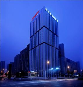 un edificio de cristal alto con luces encima en Hampton by Hilton Changsha South Railway Station West Square, en Changsha