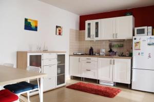 a kitchen with white cabinets and a table and a refrigerator at Balaton Holiday Home in Balatonmáriafürdő