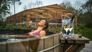 a woman in a hot tub with a glass of wine at La Belle Folie in Ploemel