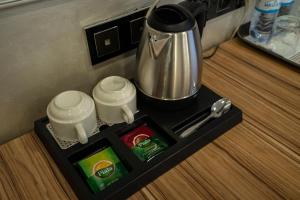 una bandeja con dos tazas y una cafetera en una mesa en Mildom City Hotel, en Almaty