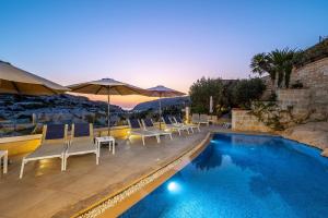 a swimming pool with chairs and umbrellas on a resort at Viewpoint Boutique Living in Xlendi