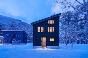 a black house with a door in the snow at Powdersuites in Hakuba