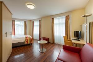 a hotel room with a bed and a red couch at Hotel De la Paix in Lucerne