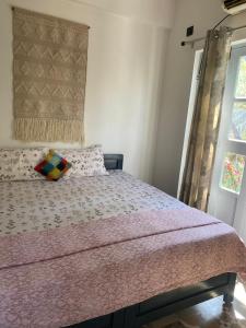 a bedroom with a bed with a pink bedspread and a window at 1 bed peaceful studio Apartment near Colva beach in Benaulim
