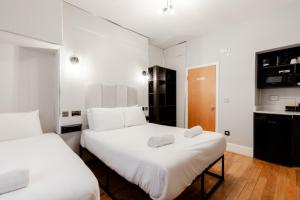 two beds in a room with white walls and wooden floors at Britannia Hyde Park Hotel in London +25 photos