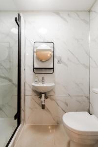 a white bathroom with a sink and a toilet at Britannia Hyde Park Hotel by PLI in London +268 photos