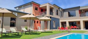 a house with a pool and some chairs and umbrellas at Karoo Sun Guest House in Oudtshoorn