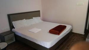 un letto bianco con un asciugamano marrone di The Wild Tiger Resort a Jyoti Gaon