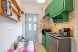 a kitchen with green cabinets and a sink at Lotus Apartment 1 in Corfu