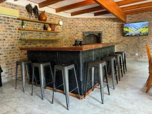 a bar with stools in a room with a brick wall at Ukujabula in Groblersdal
