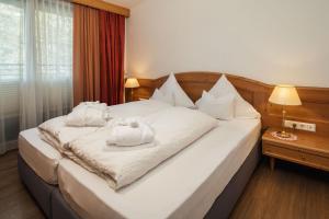 a bedroom with a large white bed with towels on it at Hotel Garni Alpenruh-Micheluzzi in Serfaus