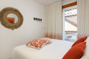 ein weißes Bett mit einem Kissen und einem Spiegel in der Unterkunft Portopiccolo Apartments - Telgatino nel Golfo in Sistiana + 25 Fotos