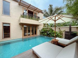 a swimming pool with a table and an umbrella at Adhisthana Villas in Borobudur