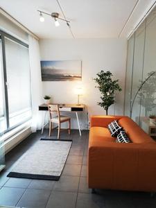 a living room with an orange couch and a table at Kotimaailma Two bedroom apartment with private sauna in Vaasa