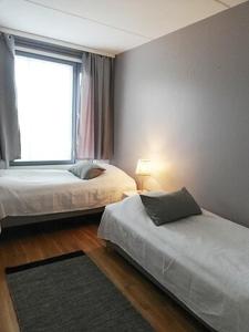 a bedroom with two beds and a large window at Kotimaailma Two bedroom apartment with private sauna in Vaasa