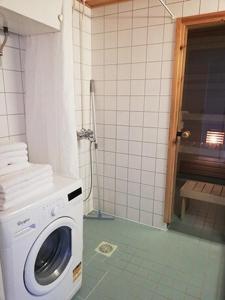 a washing machine in a bathroom with a shower at Kotimaailma Two bedroom apartment with private sauna in Vaasa