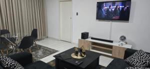 a living room with a couch and a tv on the wall at Hungwe Apartment in Harare