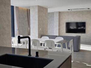 a kitchen with white chairs and a table and a tv at 펜톤나인 해변열차 송정2호점 in Busan