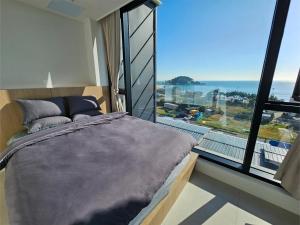 a bedroom with a bed and a large window at 펜톤나인 해변열차 송정2호점 in Busan