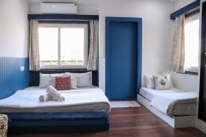two beds in a room with blue walls and windows at Blue Door in Būndi