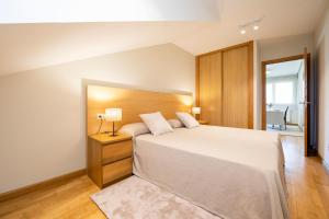 リャネスにあるApartamento Luz de Ponienteの木製のヘッドボードが付いた大きなベッドのある寝室