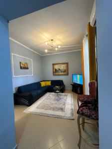 a living room with a blue couch and a tv at Vladi's Home in Çorovodë