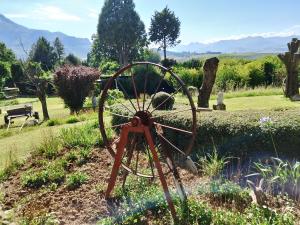 a metalwheel in a garden with mountains in the background at Gentle Presence Cottage 2 - Garden Unit in Clarens