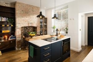 a kitchen with black cabinets and a brick wall at The Residence, Luxury City Stay in York