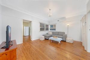 a living room with a couch and a tv at Sans Souci 4-Bedroom Home Near Beach in Sydney