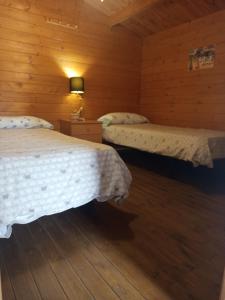 two beds in a room with wooden walls at Centro ecuestre Girasol in Chiclana de la Frontera