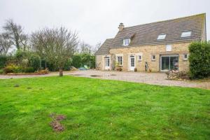 Una casa de ladrillo con un gran patio delante de ella. en Appartement cosy à Sainte-Marie-du-Mont avec jardin 25m², en Sainte-Marie-du-Mont