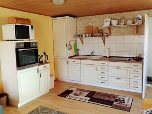 a kitchen with white cabinets and a microwave at Ferien am Hegensteinbach in Fürstenberg +10 photos