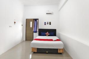 a bedroom with a bed in a white room at YUTAKA INN Bypass Mojokerto in Mojokerto +3 photos