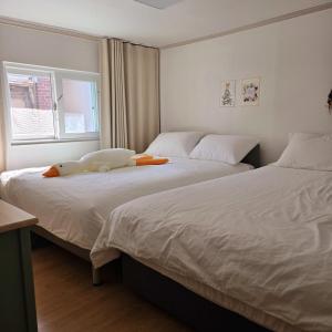 Dos camas con un animal de peluche sentado encima de ellas. en Kozy Stay,신당역도보4분,동대문,ddp,명동,홍대,경복궁,서울타워,종로,강남,이태원,잠실,K-pop, en Seúl 50 fotos más