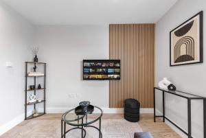 a living room with a glass table and a wall at Warm & Bright Studio, Easy Commute to Central in New Southgate