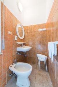 W łazience znajduje się umywalka, toaleta i lustro. w obiekcie Hotel Falco w mieście Riccione