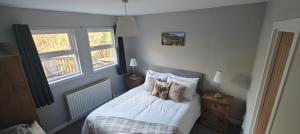 a bedroom with a bed with white sheets and pillows at Ben Lomond Cottage in Arrochar