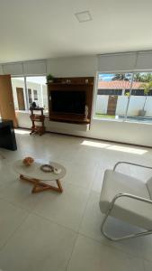 Una sala de estar con un televisor, un sofá y una mesa. en Casa Mar Sonho Verde, en Paripueira 119 fotos más