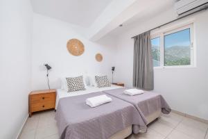 a white bedroom with two beds and a window at Einalia Holiday Homes by the Beach in Kardamaina