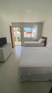 a bedroom with two beds and a television in it at Casa Mar Sonho Verde in Paripueira +119 photos