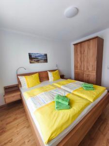 a large bed with yellow sheets and green towels on it at Ferienhaus Marianne in Zinnowitz