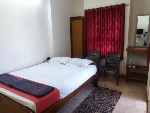 a bedroom with a bed and a red curtain at Visvam Guest House in Mayiladuthurai