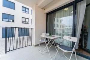 d'un balcon avec une table blanche et deux chaises. dans l'établissement Flex SelfCheckIns 98 - Zagreb - 2 Bedrooms - Parking - Loggia, à Velika Mlaka