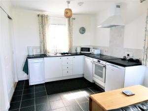 a kitchen with white cabinets and a black counter top at Crossroads Cottage in Sollas