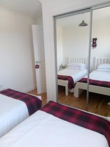 a bedroom with two beds and a mirror at Crossroads Cottage in Sollas