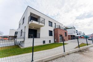 un bâtiment blanc avec une clôture devant dans l'établissement Flex SelfCheckIns 98 - Zagreb - 2 Bedrooms - Parking - Loggia, à Velika Mlaka