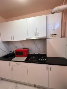 a kitchen with white cabinets and a red microwave at Studio Turda in Turda +1 photo