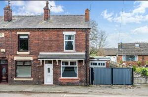 a brick house with a black fence in front of it at Comfortable Cottage in Greater Manchester in Glazebury