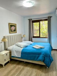 a bedroom with a blue bed and a window at Melhor sobrado de Gramado 600m da Rua Coberta in Gramado