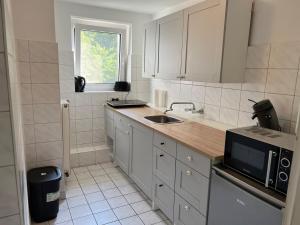 a white kitchen with a sink and a microwave at Wohnung mit Balkon am Rhein in Düsseldorf +14 photos